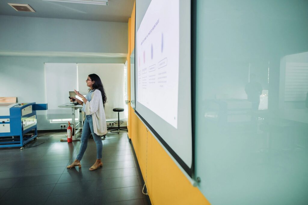 Side view of asian indian smiling female student presenting in college classroom