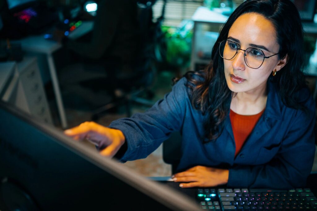 Latina cybersecurity analyst focused on computer screen at night