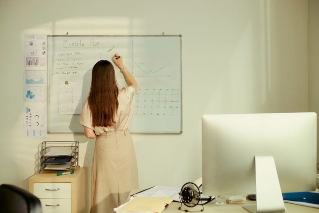 Adult Woman Writing Monthly Plan on Whiteboard in Office